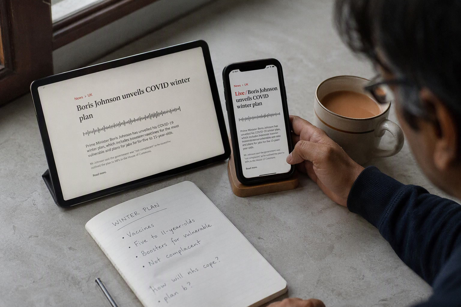 Tablet and phone showing news-style coverage of a text-to-speech launch beside a notebook of notes